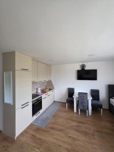 a kitchen with white cabinets and a table and chairs at Apartmani gradina Tuzla in Tuzla