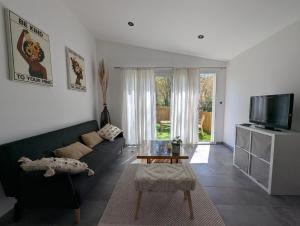 a living room with a black couch and a tv at Les Nuits Nordiques in Bras