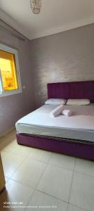 a bed with a purple headboard in a bedroom at Appartement à louer wadie in Fnidek +12 photos