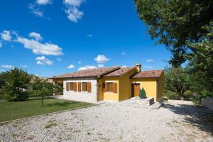 a small yellow house with a gravel driveway at Vila Charlie in Labin