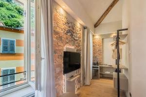 a living room with a stone wall and a flat screen tv at La Corte Del Lario - San Giorgio in Varenna