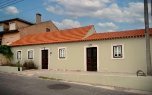 a white house with an orange roof on a street at Casa do Ti Maurício in Gondemaria