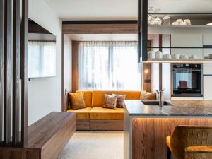 a kitchen and living room with a yellow couch at Corones Suites - Dolomites Residence in Valdaora