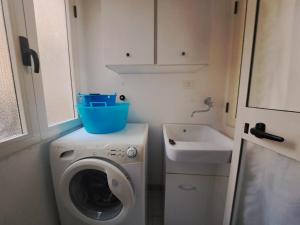 a small bathroom with a washing machine and a sink at S'erribera de S'abiolu in Baunei