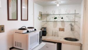 a small kitchen with a sink and a microwave at Suíte no Centro de Caxambu - Poucos metros do Parque in Caxambu +50 photos
