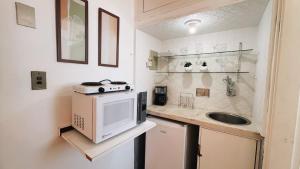 a small kitchen with a microwave and a sink at Suíte no Centro de Caxambu - Poucos metros do Parque in Caxambu
