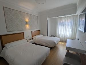 a hotel room with two beds and a desk at Hostal La Mexicana in Santander +131 photos