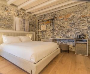 a bedroom with a bed and a stone wall at La Corte del Lario - Contrada dei Sarti in Varenna
