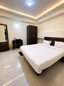 a bedroom with a large white bed and a desk at The Bliss Hotel and Restaurant in Gangtok