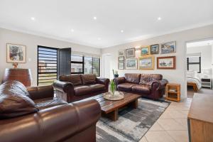 a living room with leather couches and a table at 8 on Nivenia in Bettyʼs Bay
