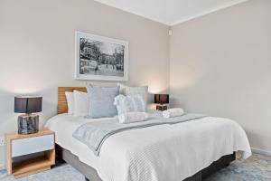 a white bedroom with a large white bed with pillows at 8 on Nivenia in Bettyʼs Bay