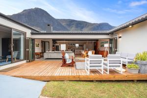 a wooden deck with chairs and a living room at 8 on Nivenia in Bettyʼs Bay
