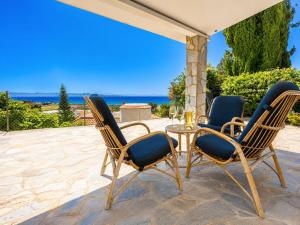 a patio with three chairs and a table with a view of the ocean at Argaka Sunset Villa in Argaka