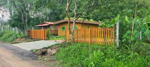 a yellow house with a fence next to a road at Cabana Refúgio do Hobbit-Gramado @refugiodohobbit in Gramado