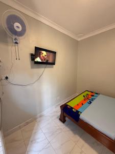 a bedroom with a bed and a fan on the wall at Crown Motel Lugala in Kampala