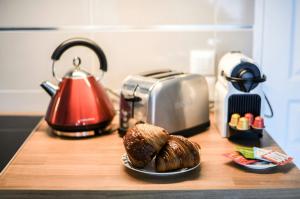 a counter with a toaster and a plate of pastries at T2 Cocon Prestige Lyonnais : Sécurité Commodités in Vénissieux +18 photos