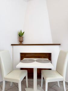 a white table and two chairs in front of a fireplace at S'Olivare Posada - Apartments in Posada