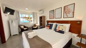a bedroom with a large bed with towels on it at Pousada Farol do Rosa in Praia do Rosa