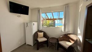 a room with two chairs and a refrigerator and a window at Pousada Farol do Rosa in Praia do Rosa