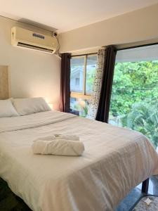 a bedroom with a white bed with a window at Daffodil in Anjuna