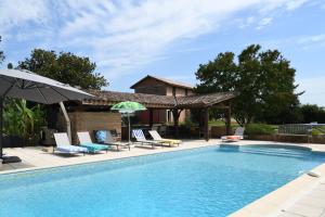 a pool with chairs and umbrellas next to a house at Domaine familial, Le Parc de Gouts in Aiguillon