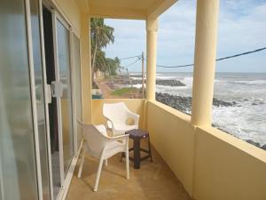 a balcony with two chairs and a view of the ocean at Inuli Coco Hut in Kalutara +29 photos
