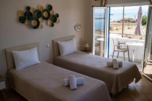 two beds in a room with a view of the ocean at Pelagia Beach Studios in Agia Pelagia
