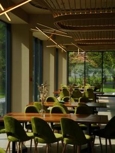 a dining room with tables and green chairs at Hotel Băile Bughea in Bughea de Sus