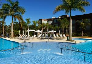 a swimming pool with palm trees and a resort at Falls Iguazú Hotel in Puerto Iguazú