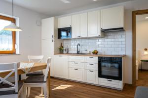 a kitchen with white cabinets and a table and a dining room at Start Point Apartments in Žirovnica