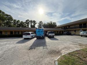 a parking lot with two cars and a blue bus at Kings Suites Near Naval Base I-95 Kingsland in Kingsland