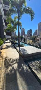a swimming pool with palm trees on a building at Opus Gyro Vaca Brava Designer in Goiânia +10 photos