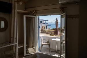 a room with a door open to a balcony with a table and an umbrella at Pelagia Beach Studios in Agia Pelagia