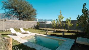 a pool with two chairs and a bench in a yard at Casa Tannat by Vindecaf in Cafayate