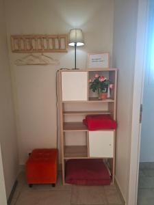 a room with a shelf with a lamp and flowers at Studio Lumineux avec jardin & piscine à Vaison la Romaine in Vaison-la-Romaine