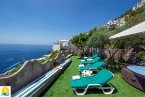 a row of lounge chairs sitting on the grass near the ocean at Casa Francisca in Praiano
