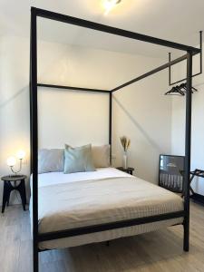 a bedroom with a black canopy bed with white sheets at OverGarden Rooms in Dossobuono