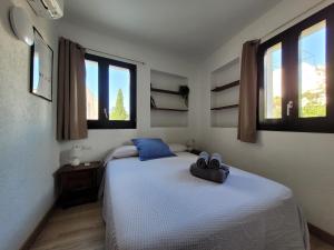 a bedroom with a bed with blue pillows and windows at Jengina, muy centrico in Cadaqués