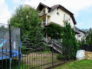 a house behind a fence with a dog on the balcony at B&B Artemida in Ostrowo
