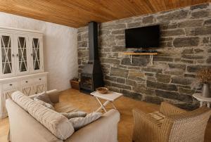 a living room with a couch and a stone wall at Casas de Xisto in Mogadouro