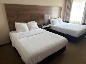 a hotel room with two beds and a lamp at Wingate by Wyndham Utica in Utica +33 photos