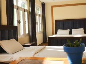 a bedroom with two beds and a vase on a table at Alpen Hotel Skardu in Skardu