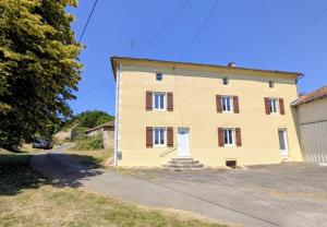 a yellow house on a road next to a building at Gîte de roger in Blond