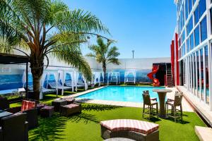 a pool with chairs and a palm tree in a building at Nkandla Lifestyle in Mthatha
