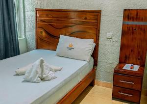 a bedroom with a bed with a wooden headboard at King Solomon Hotel in Nkunjila +3 photos