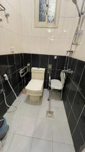 a bathroom with a toilet and a chair in it at أجنحة ورد للشقق المخدومة in Khamis Mushayt +36 photos