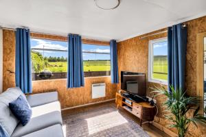a living room with a couch and a tv at Farmer's Cabin in Forfar