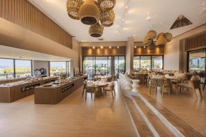 a restaurant with tables and chairs and windows at Medite Kassandra Resort in Nea Moudania