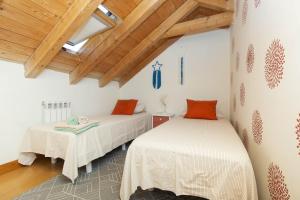 two beds in a room with wooden ceilings at Casa El Mirador de Jaca in Jaca
