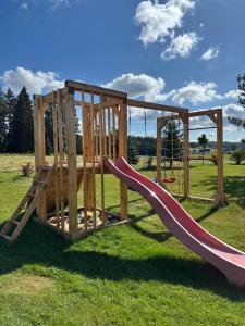 a wooden playground with a slide in the grass at Doboszowka in Lasowka
